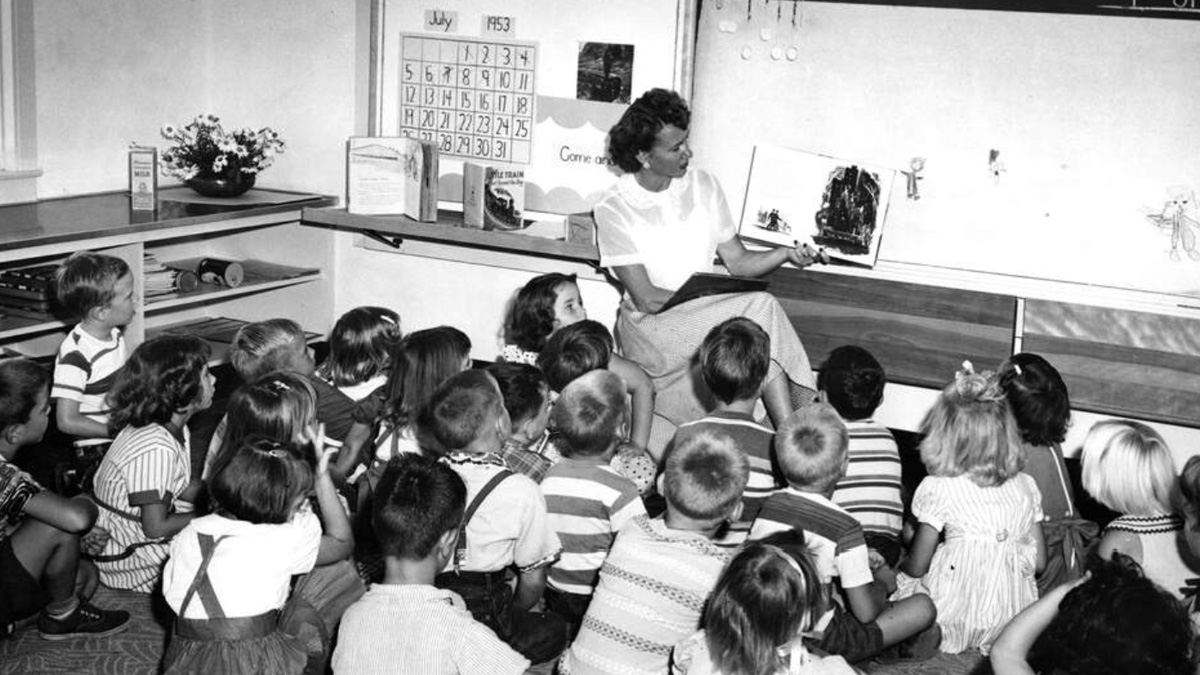 A student teacher reads a picture book to first grade children seated on a rug at the Campus Laboratory School classroom.