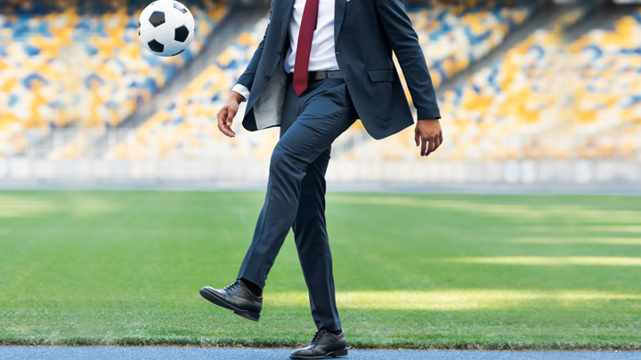business man kicking a soccer ball on the field