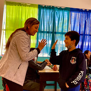An SDSU student teacher hi-fives a student in a Tijuana classroom.