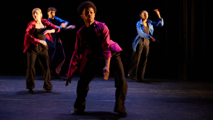 Four dancers perform on a stage.