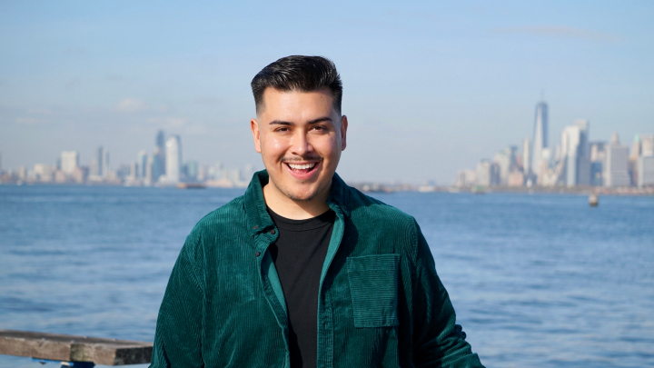 Kevin Perez smiles as he stands in front of the New York City skyline.