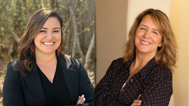 Two women in black professional attire smile with crossed arms.