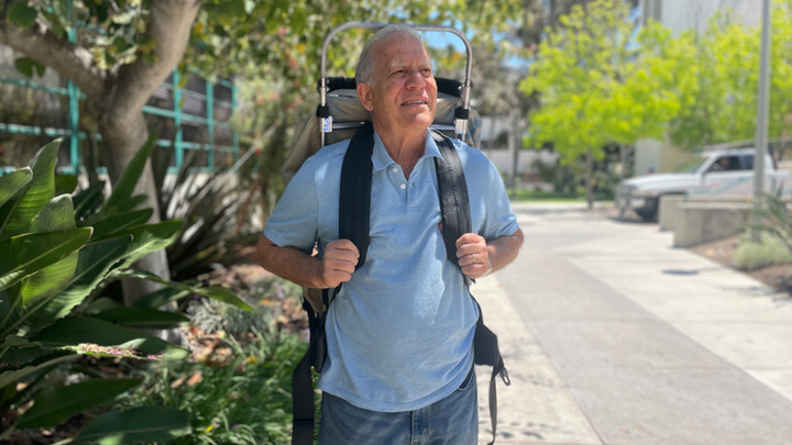 A man in a blue shirt and backpack stares into the distance.