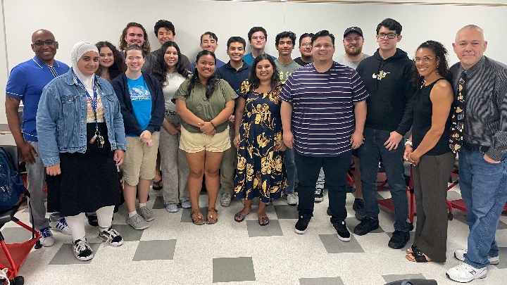 A large group of students and faculty pose in a classroom.