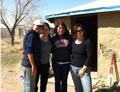 3 young women pose in front of adobe dwelling t March 2012 retreat, Shiprock, New Mexico (Tsedaak'aan, Diné Nation)
